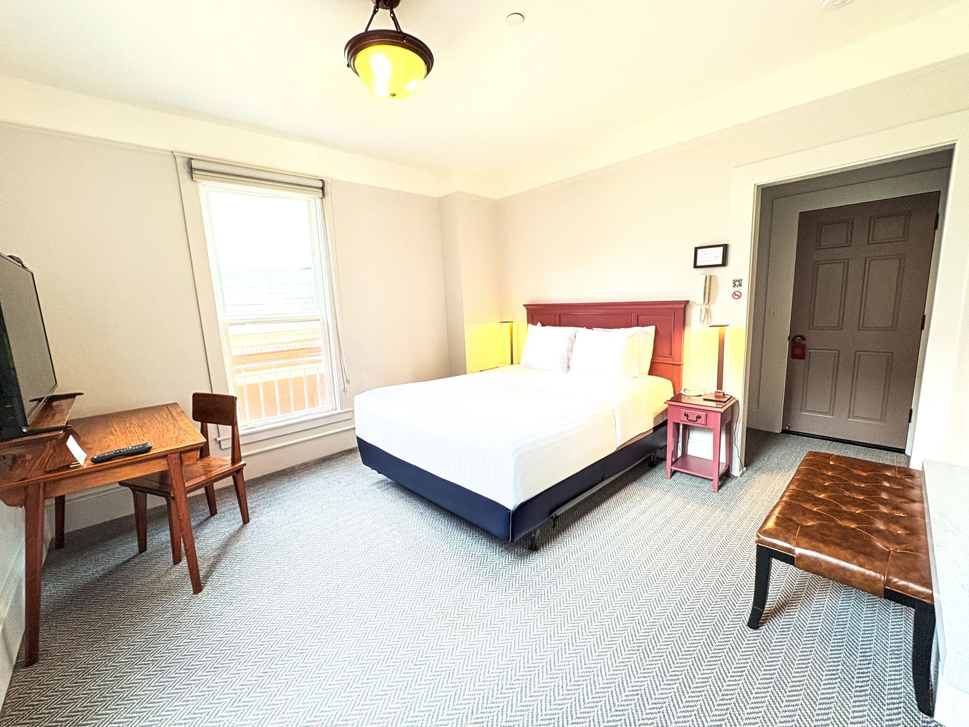 A hotel room with a king size bed , desk and chairs.