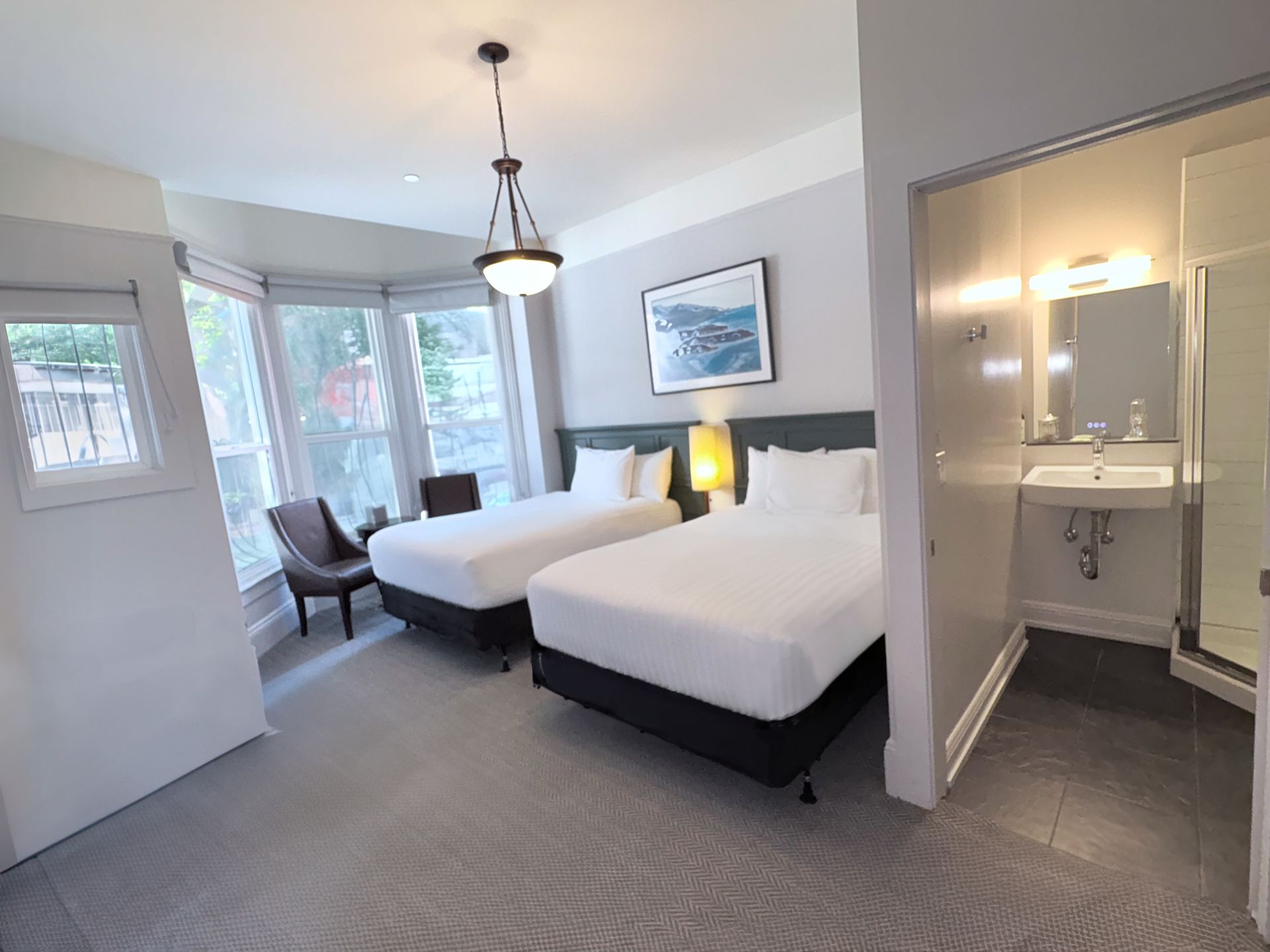 A hotel room with two beds , a chair and a sink.