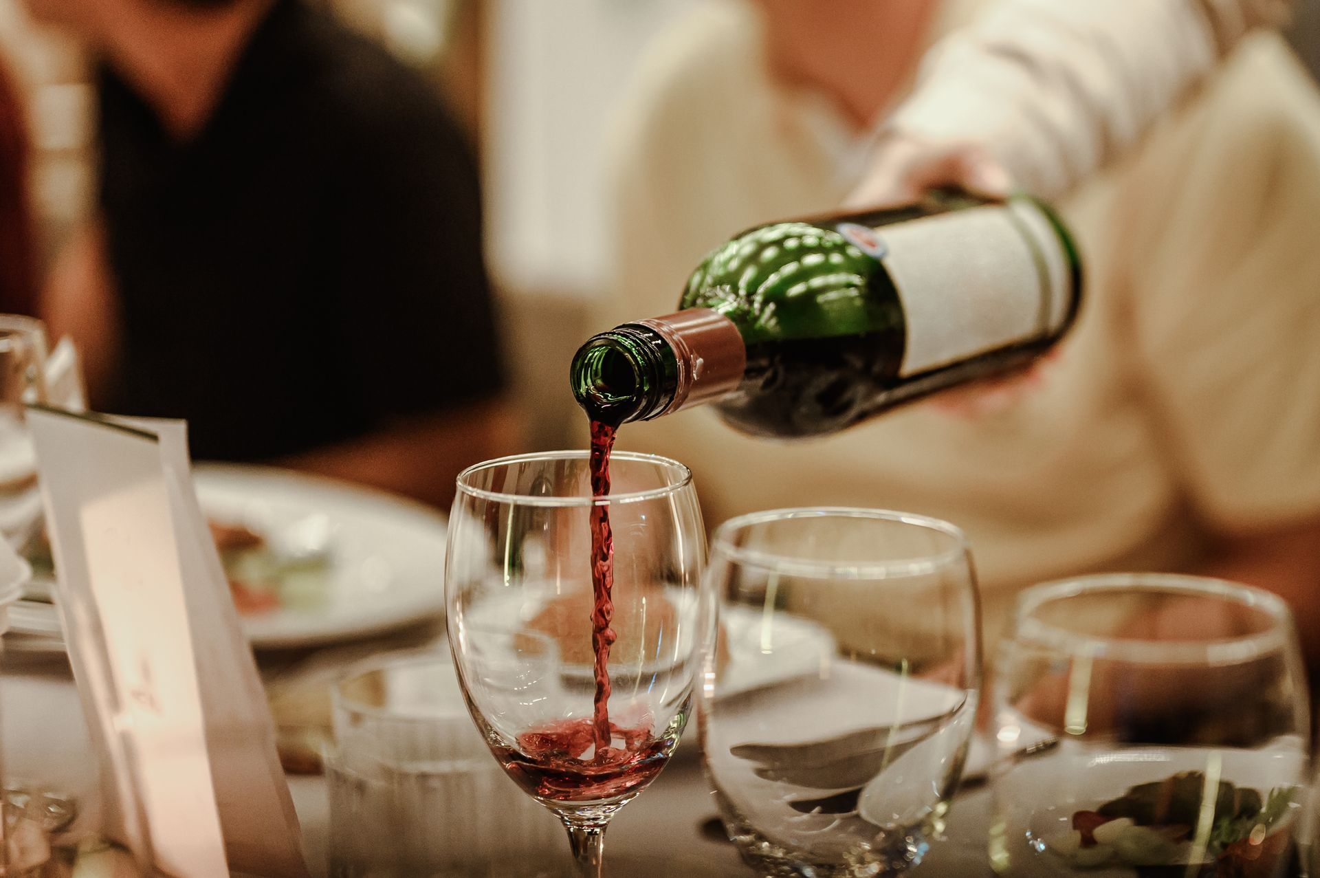A person is pouring wine into a glass on a table.
