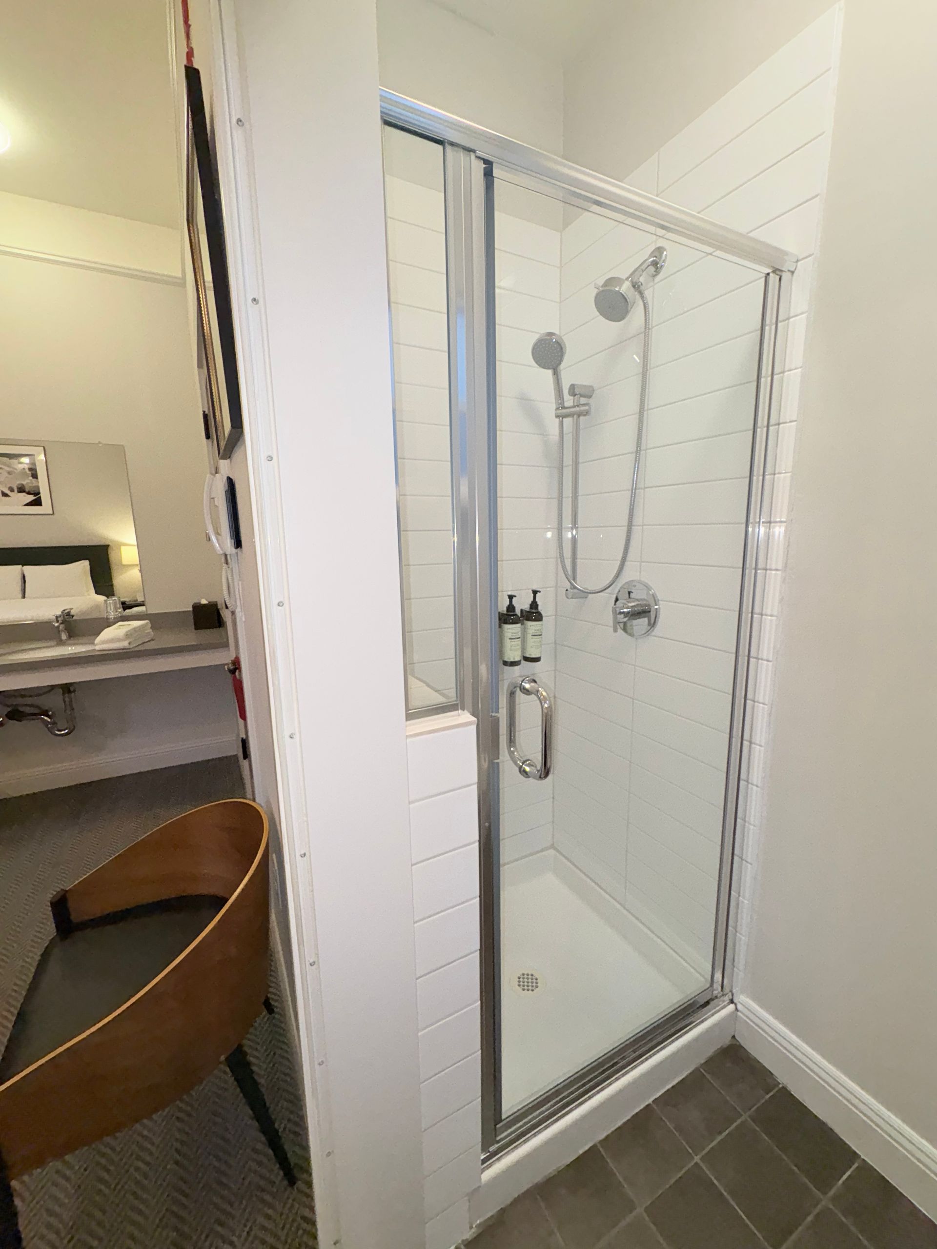 A bathroom with a walk in shower and a chair.