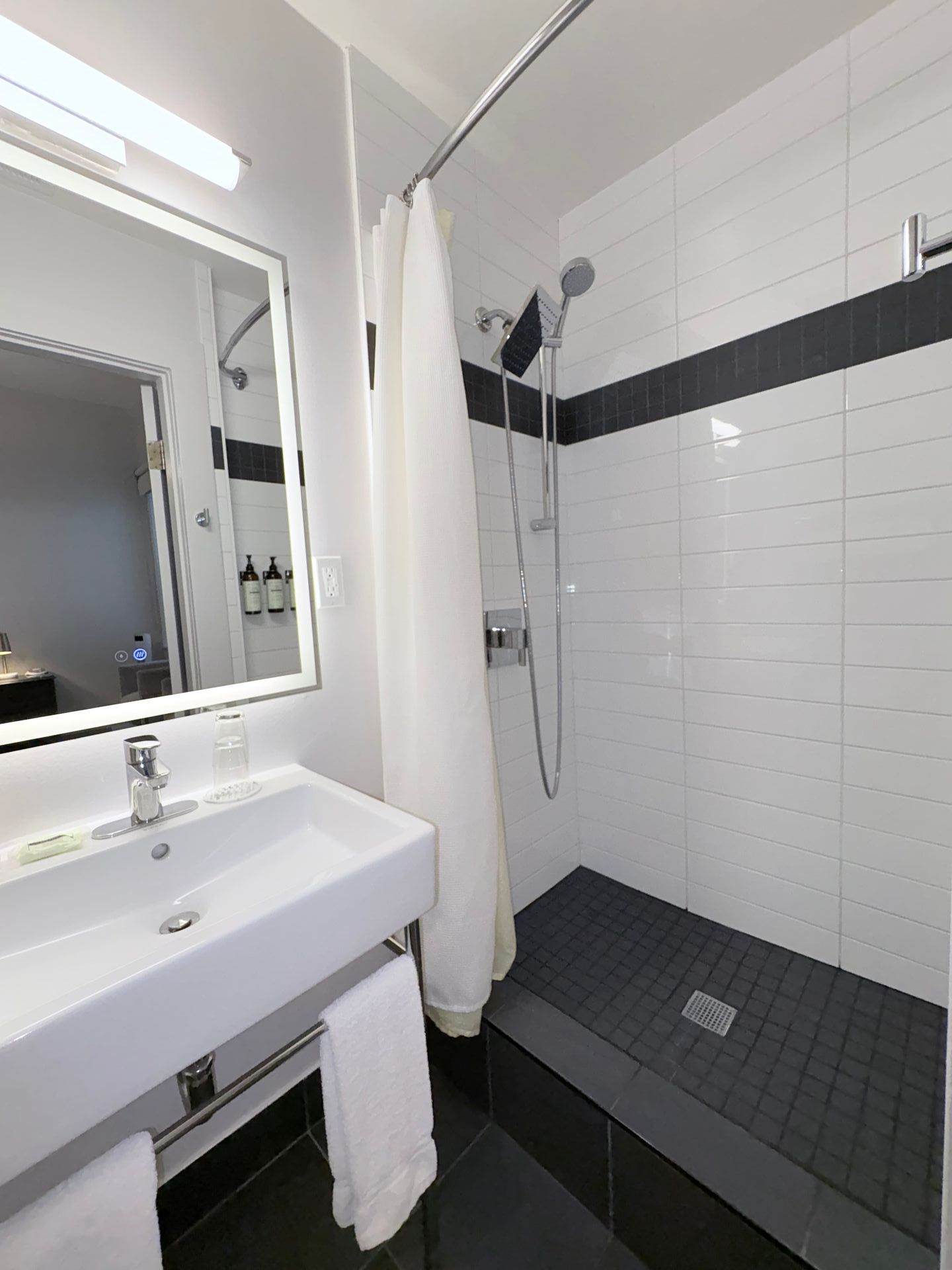 A bathroom with a sink , mirror and shower.