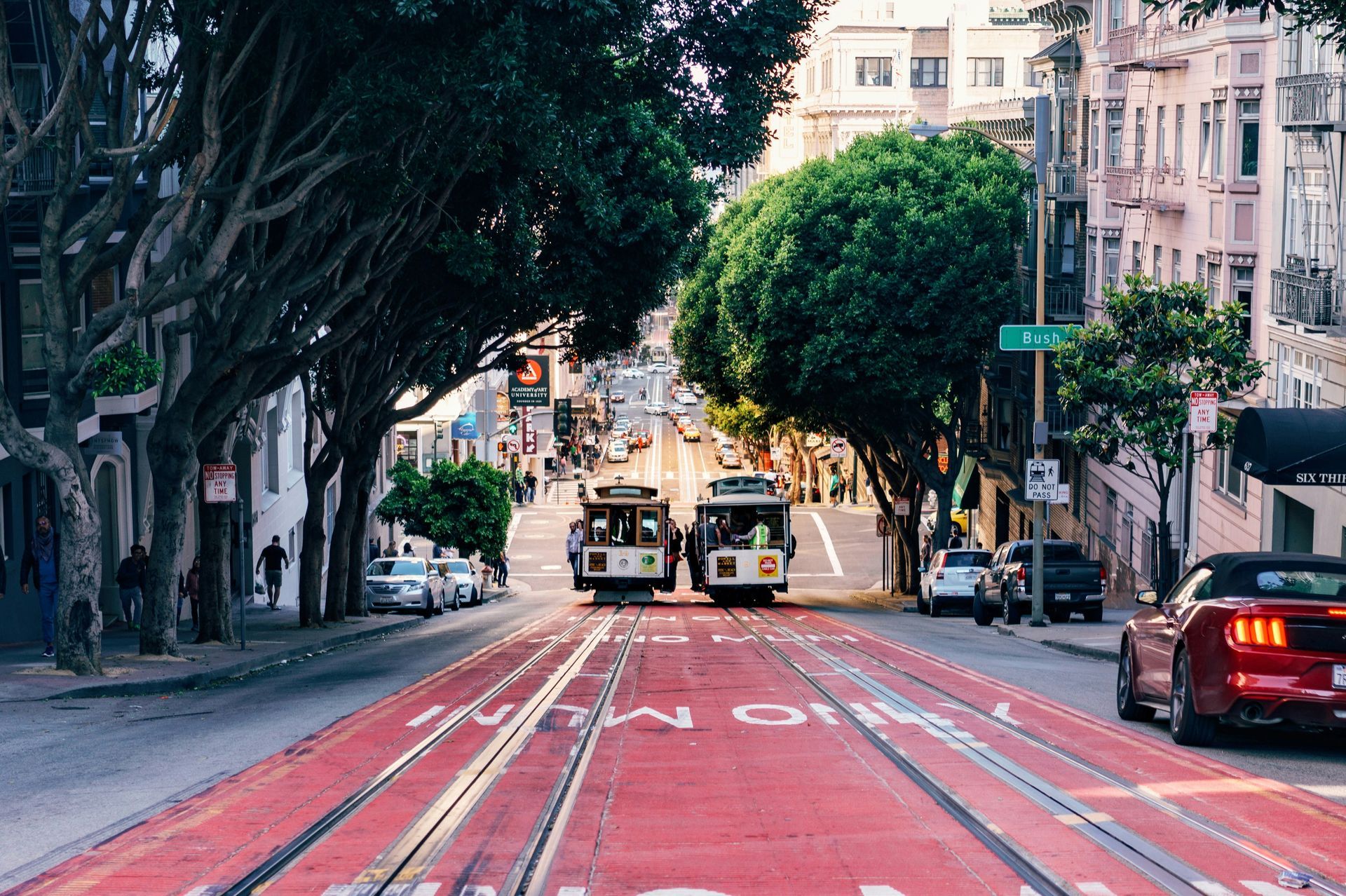 Two trolleys are driving down a city street.