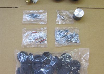 Componenti hardware, tra cui viti e tappi di gomma, in sacchetti di plastica sigillati.