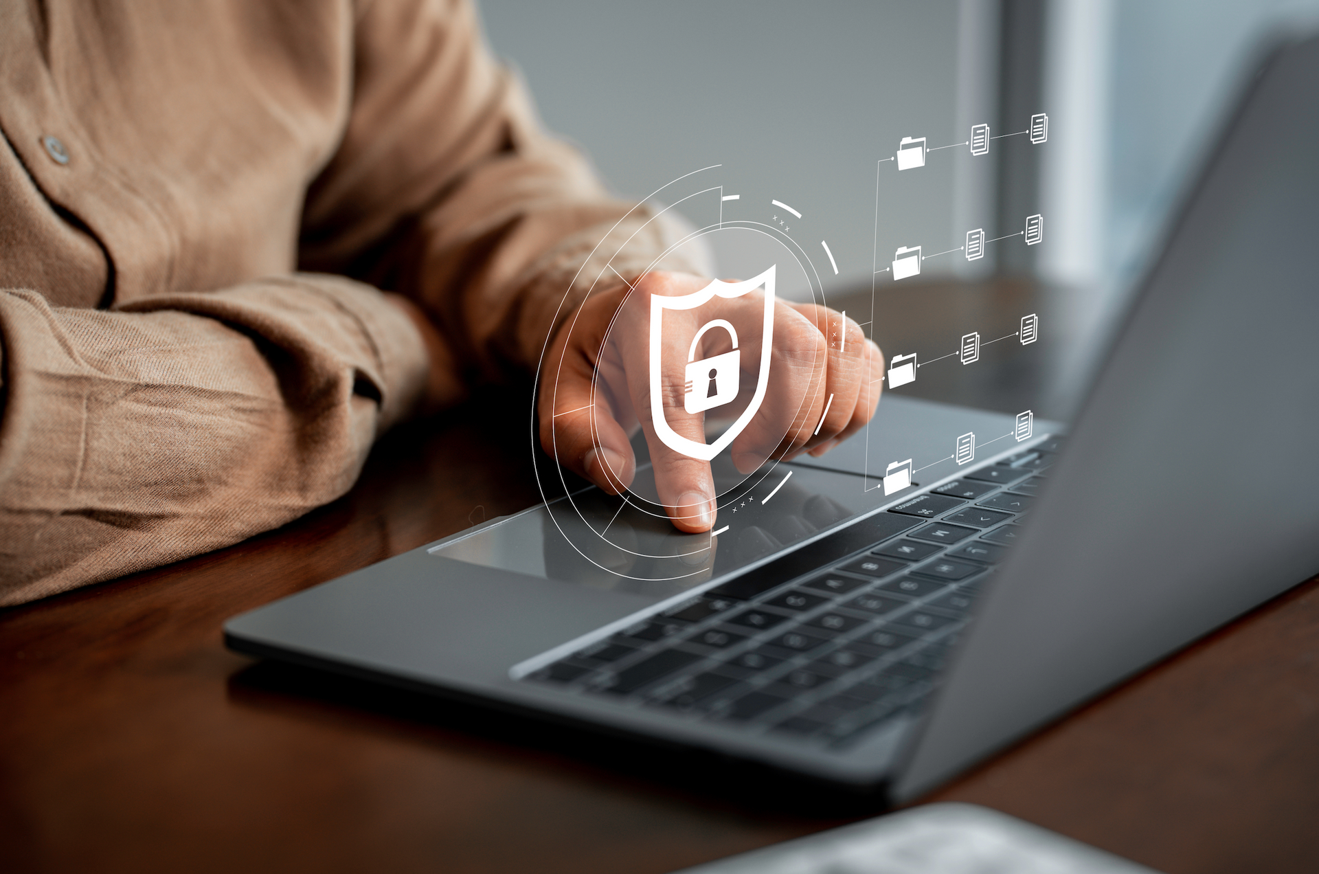 A person's hand touching a laptop with a digital security shield overlay and icons suggesting data protection.
