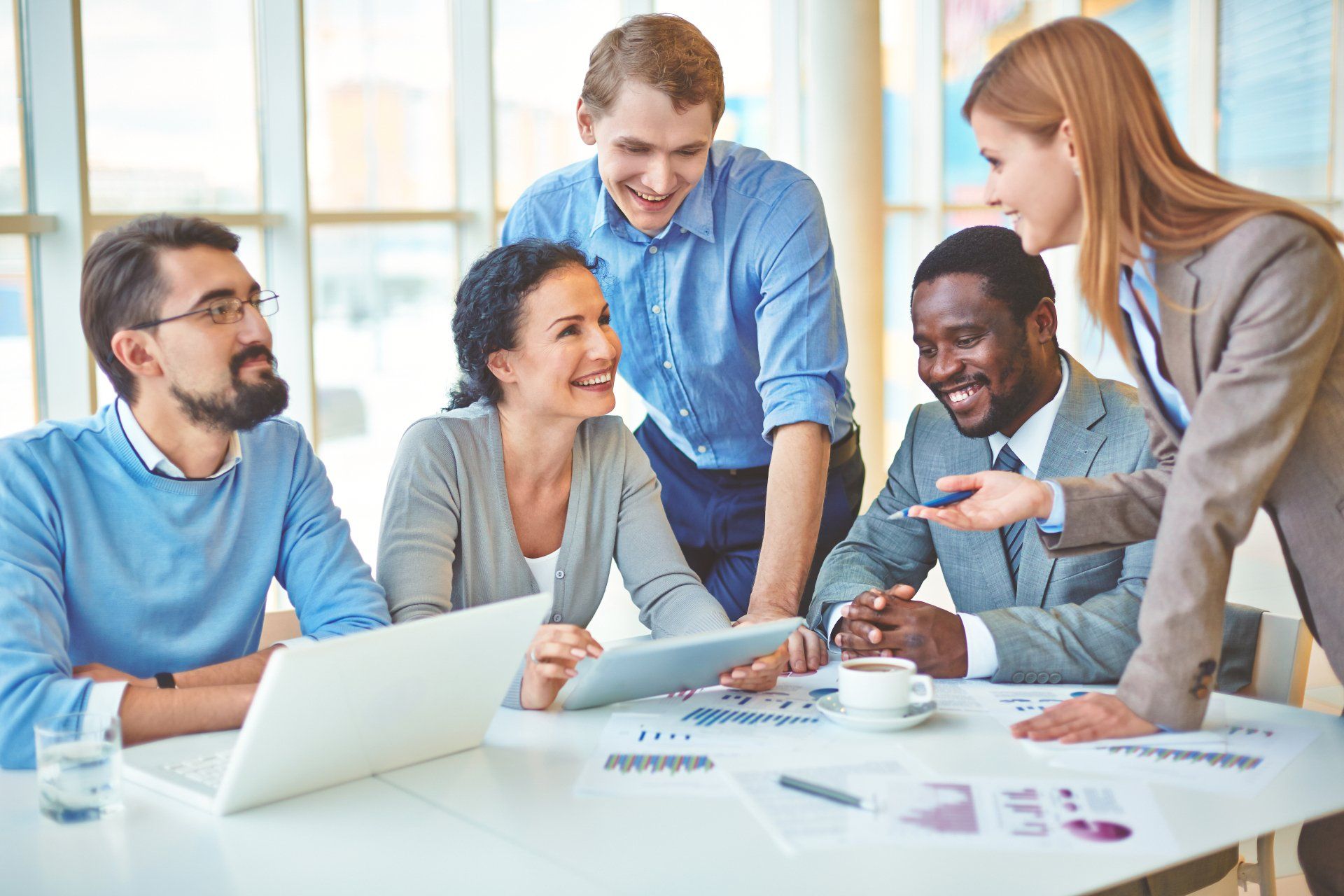A group of people are sitting around a table looking at a laptop.