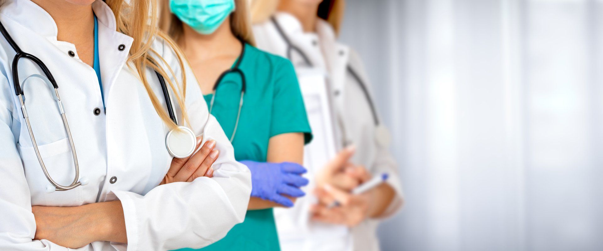 A group of doctors and nurses are standing in a row with their arms crossed.