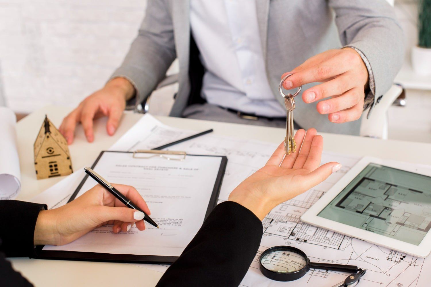 A man is giving a key to a woman who is signing a document