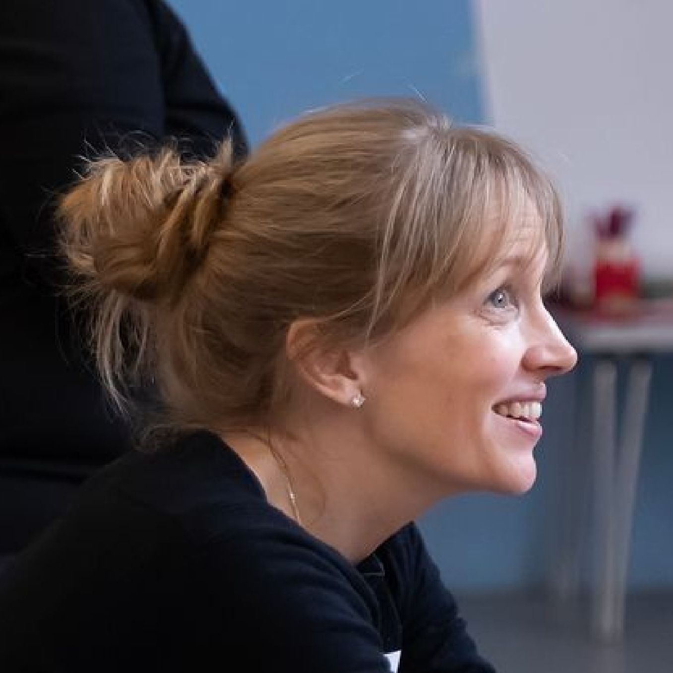 A woman with blonde hair in a bun is smiling