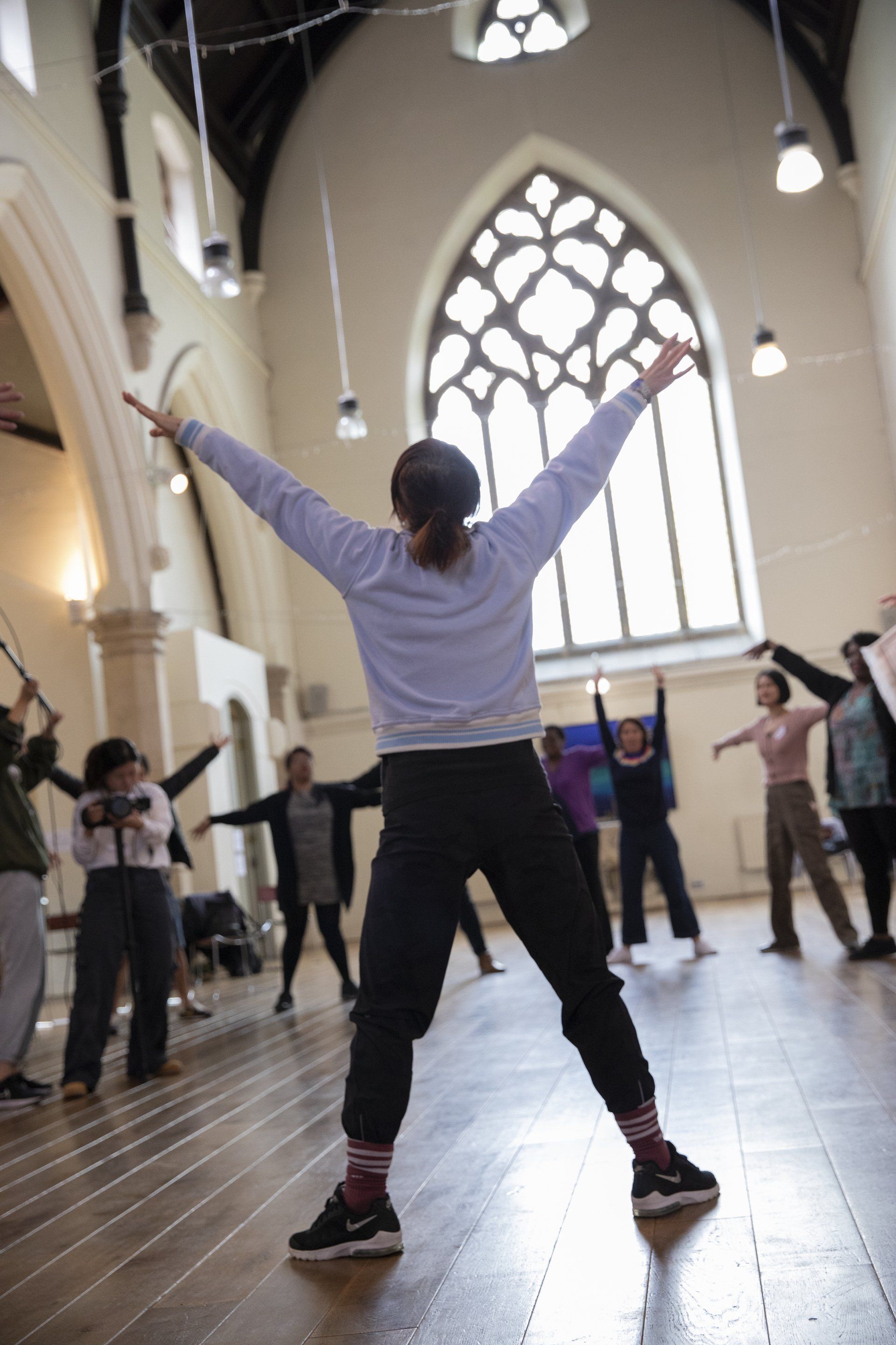 A group of people are standing in a room with their arms outstretched