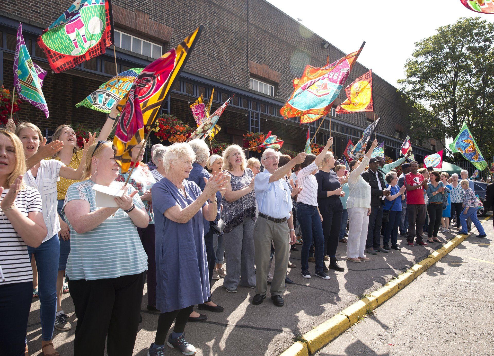 A large group of people are waving flags in front of a building.