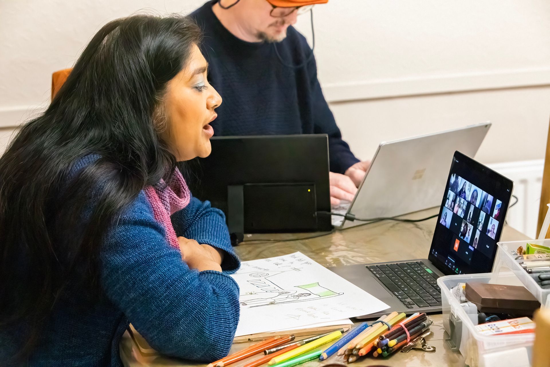 A man and a woman are sitting at a table with laptops.