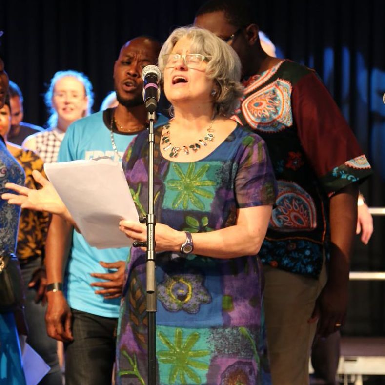 A woman singing into a microphone while holding a piece of paper