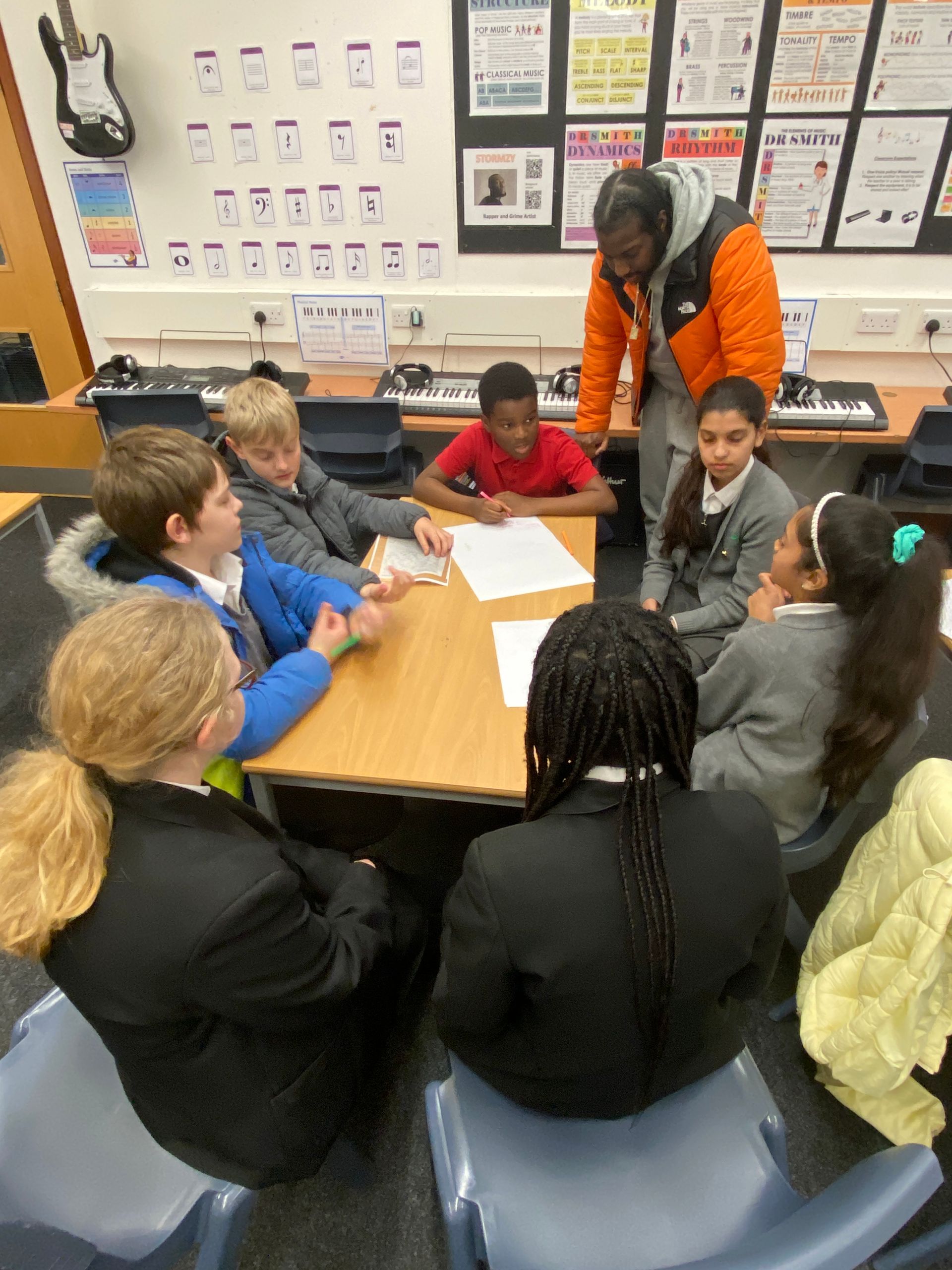 A group of children are sitting around a table in a classroom.