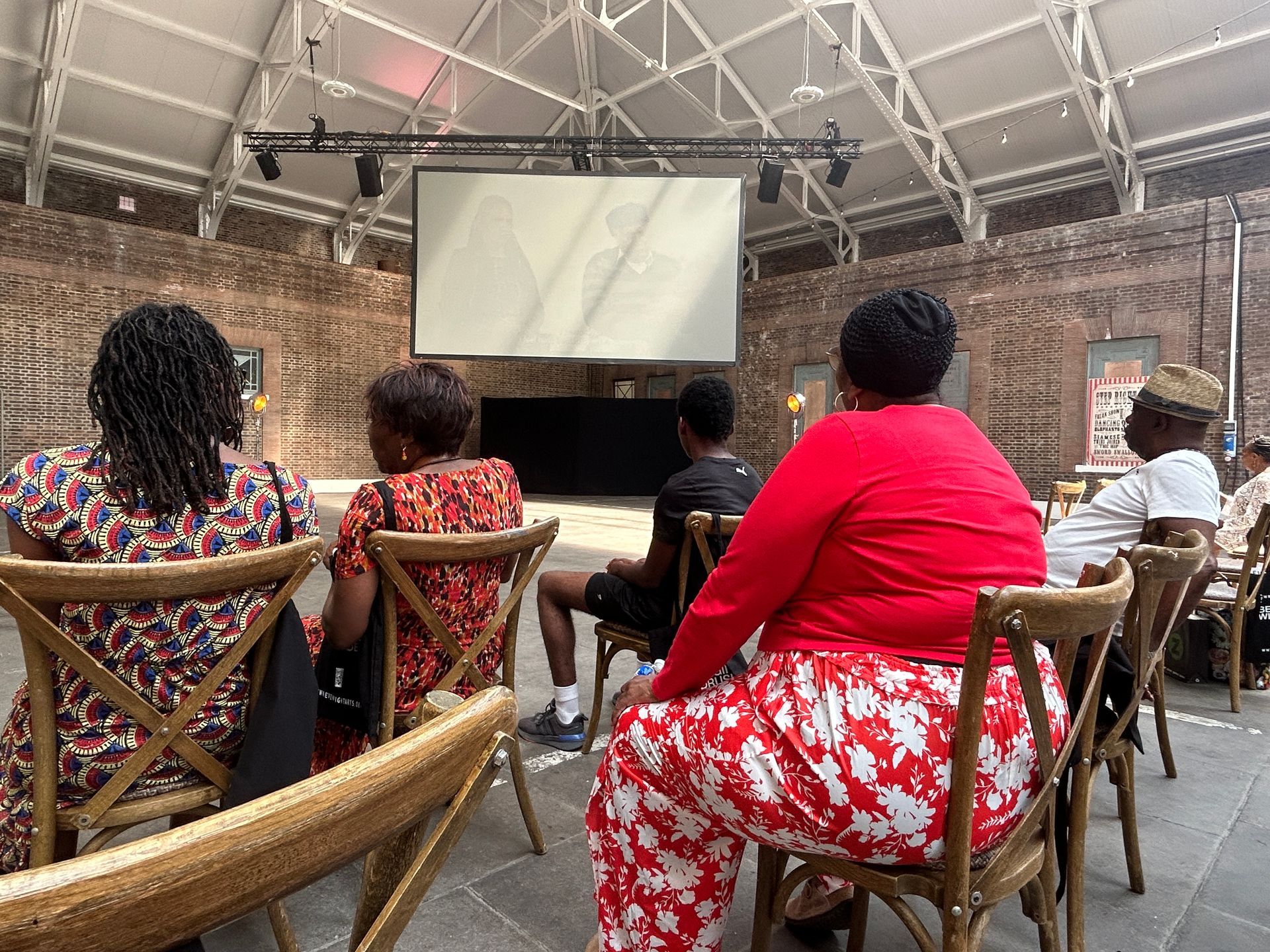 A group of people are sitting in chairs in front of a large screen.