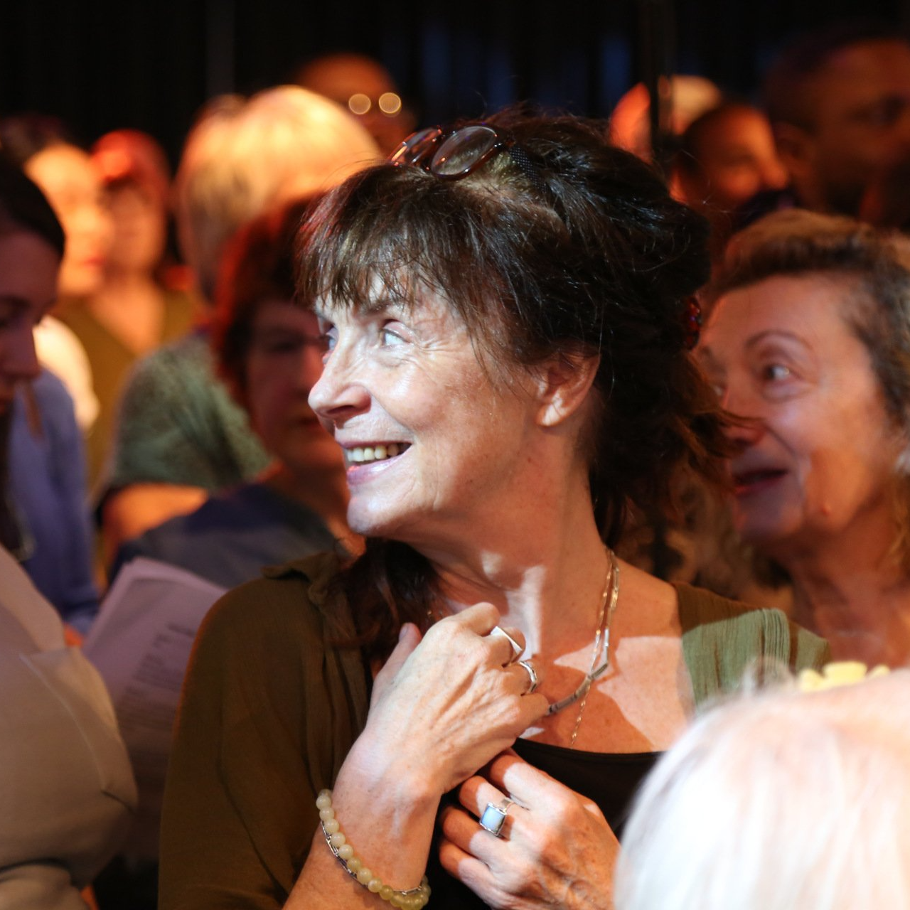 A woman in a green top is smiling in a crowd of people
