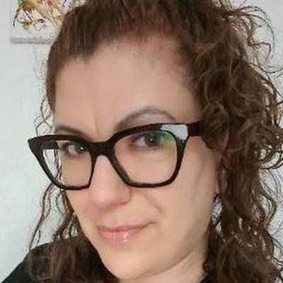 A close up of a woman wearing glasses and smiling.