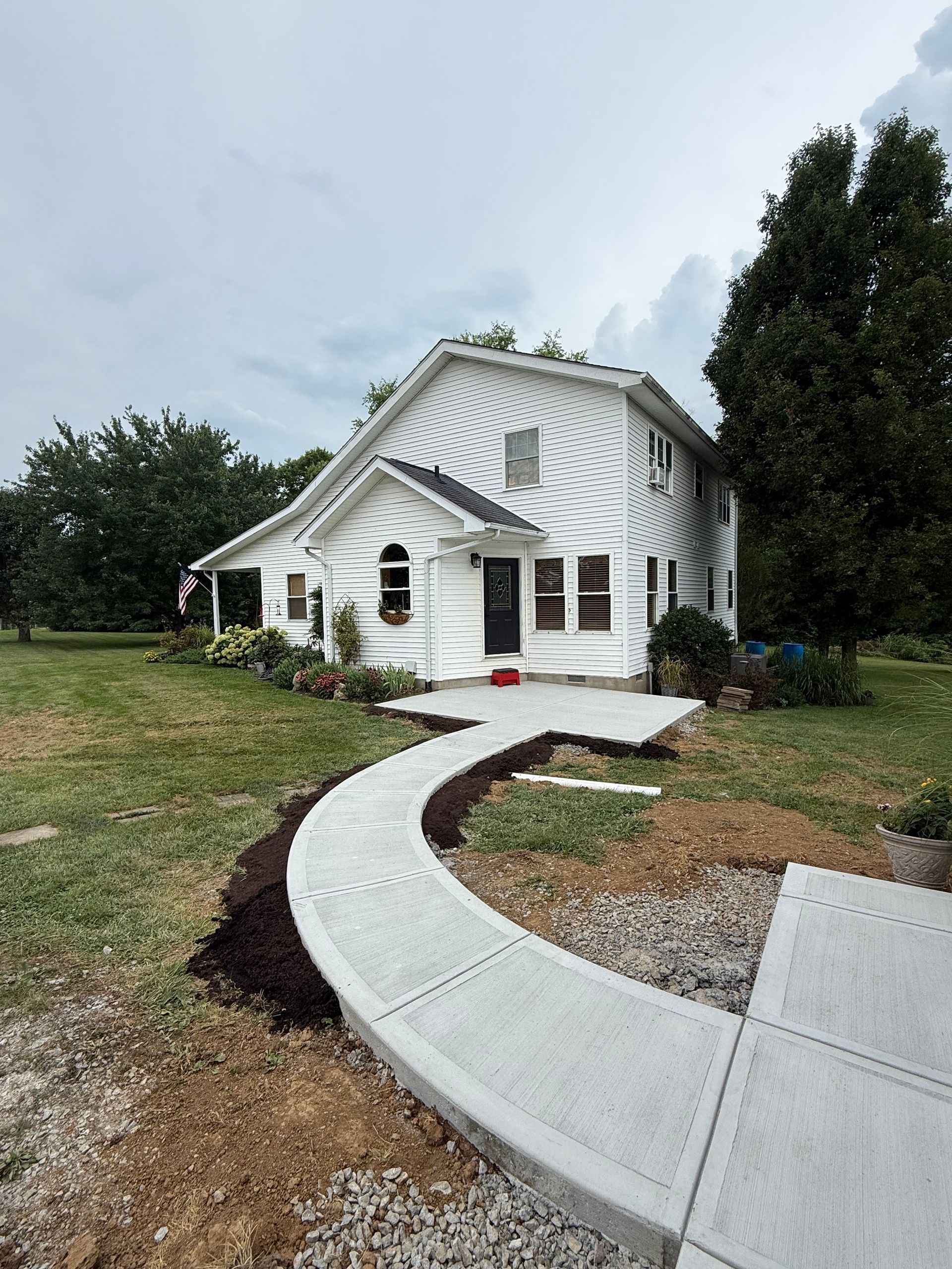 White house with a curved concrete walkway and small front porch in a grassy yard