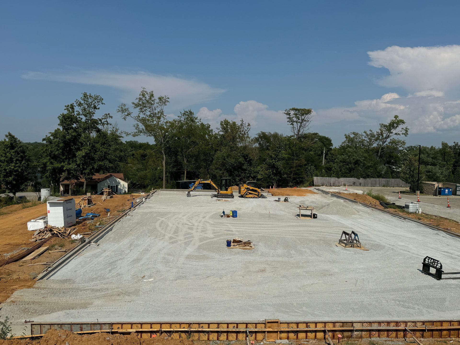 Construction site with a large concrete foundation slab under a blue sky