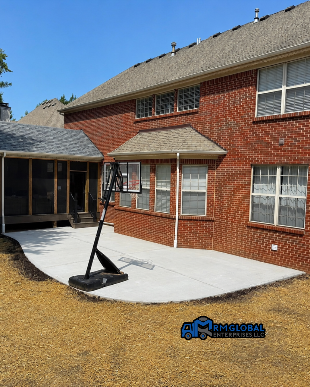 Brick house patio with a portable basketball hoop and concrete slab beside a covered walkway