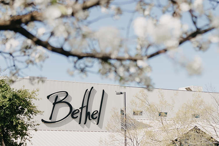 Bethel building sign on a light-colored wall with blurred white blossoms in the foreground