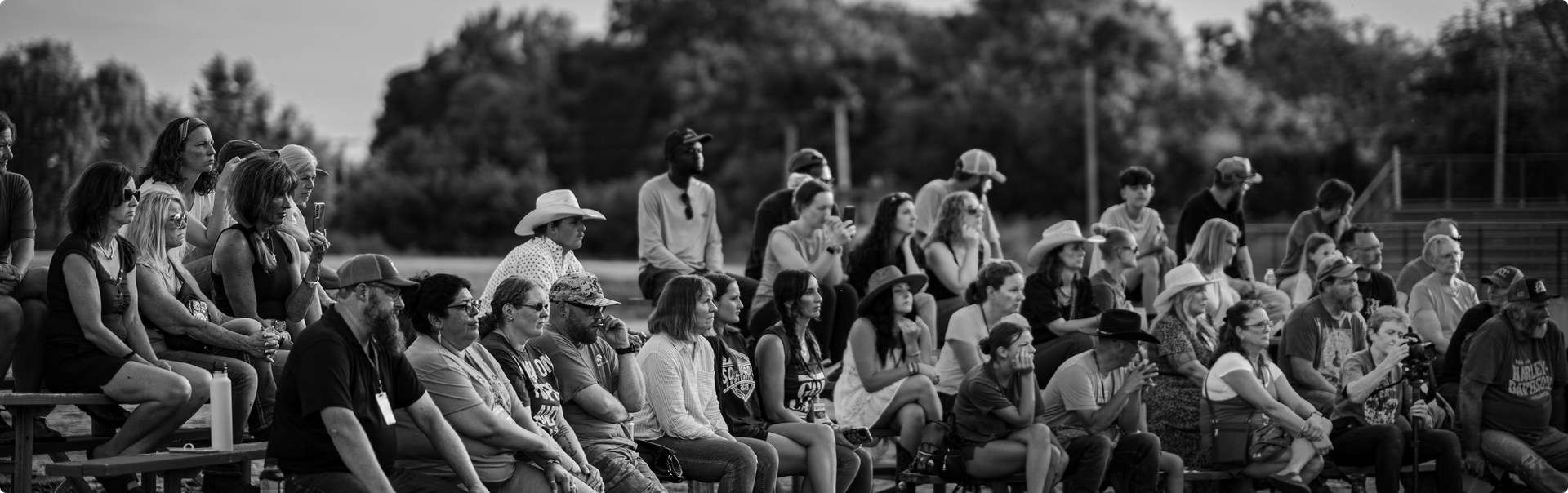 Crowd seated on outdoor bleachers watching an event in a park-like setting