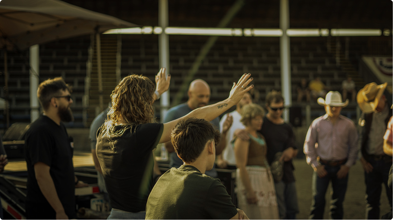 People gathered in a barn, one person raising a hand while others watch nearby.