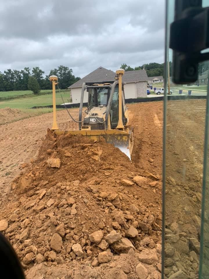 A bulldozer pushes a pile of dirt at a construction site under a cloudy sky.