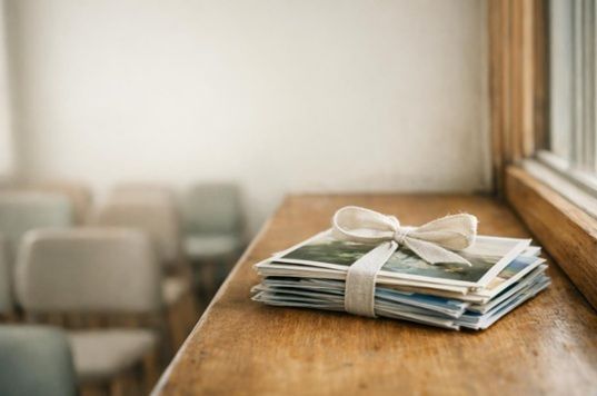 Collected family photographs tied with linen ribbon on a community room windowsill before memorial