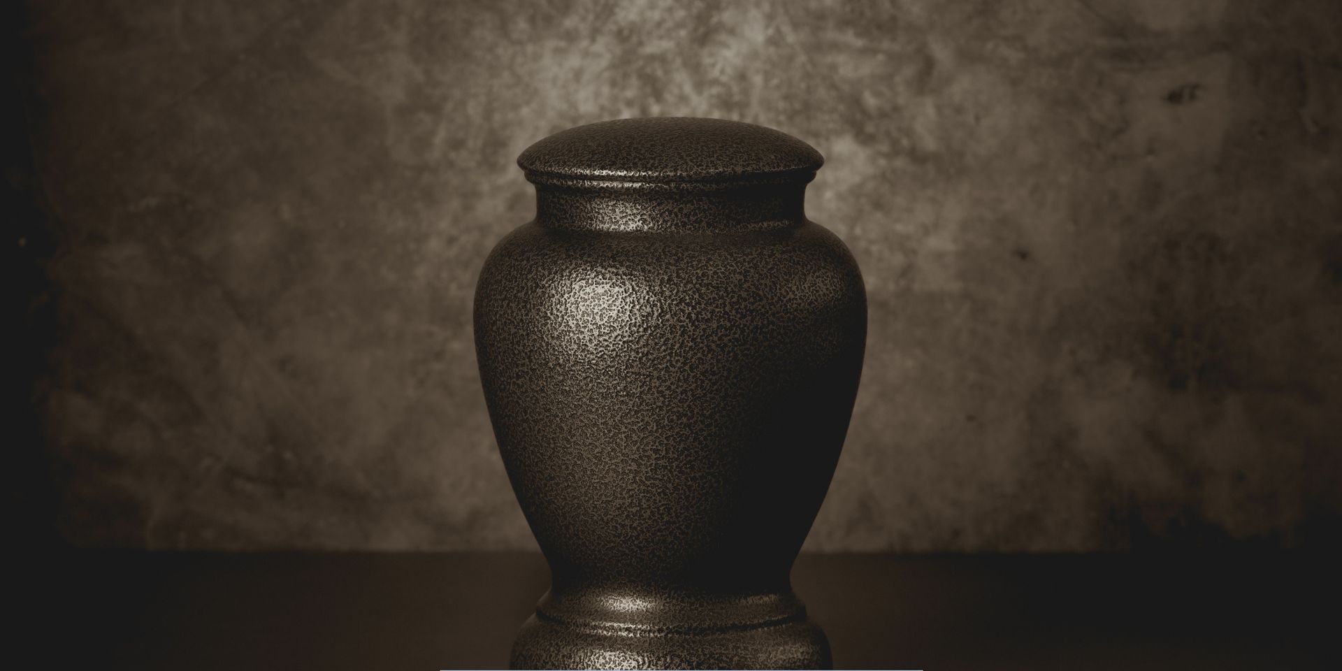 Decorative dark bronze cremation urn displayed against a textured background for Cremation Services in Cherry Hill, NJ.