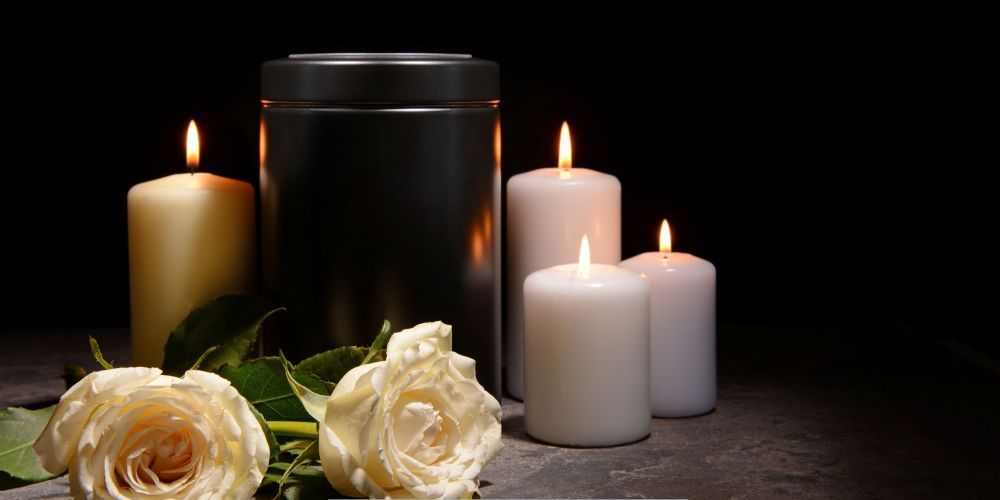 Black cremation urn with lit candles and white roses symbolizing Compassionate Cremation Services in Marlton, NJ.