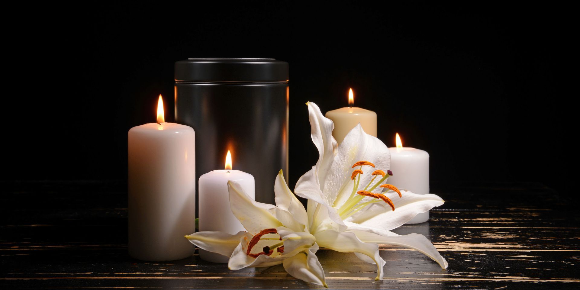 Memorial cremation urn surrounded by lit candles and white lilies representing cremation services in Voorhees Township, NJ.