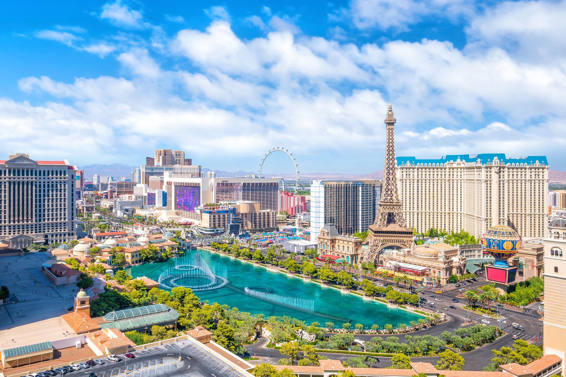Panoramic view of the Las Vegas Strip with the Bellagio fountain and turquoise lake under a blue sky