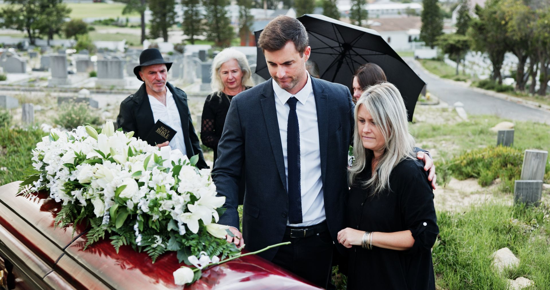 Mourners carry a wooden casket with white flowers at a funeral procession