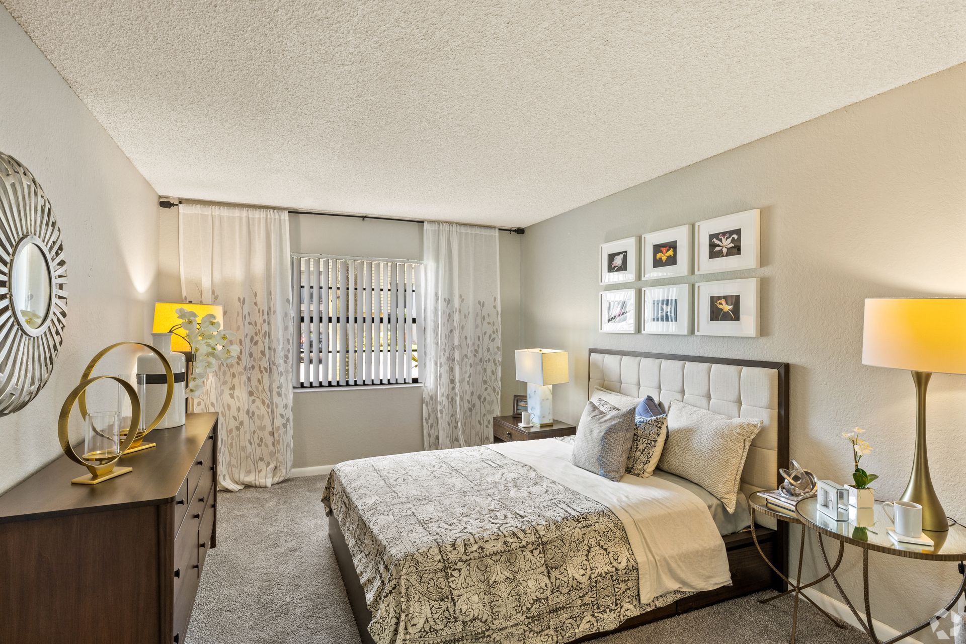 Bright, modern bedroom with a bed, nightstands, lamps, wall art, and a window with curtains at 4120 at Palm Beach Gardens Apartments in FL