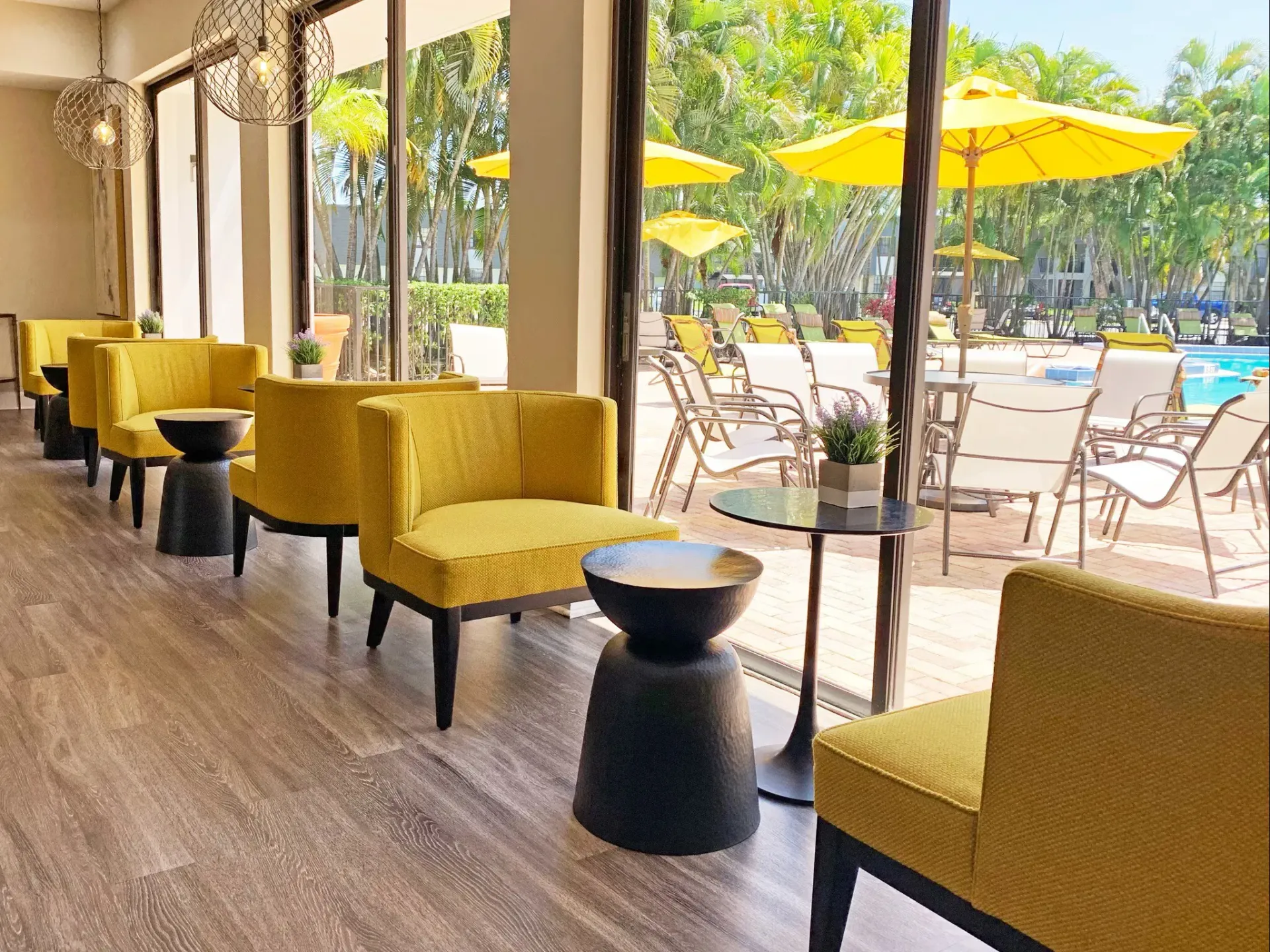 Indoor seating area with yellow chairs overlooking the pool and patio at Turnbury at Palm Beach Gardens, offering apartments in Palm Beach Gardens, FL.