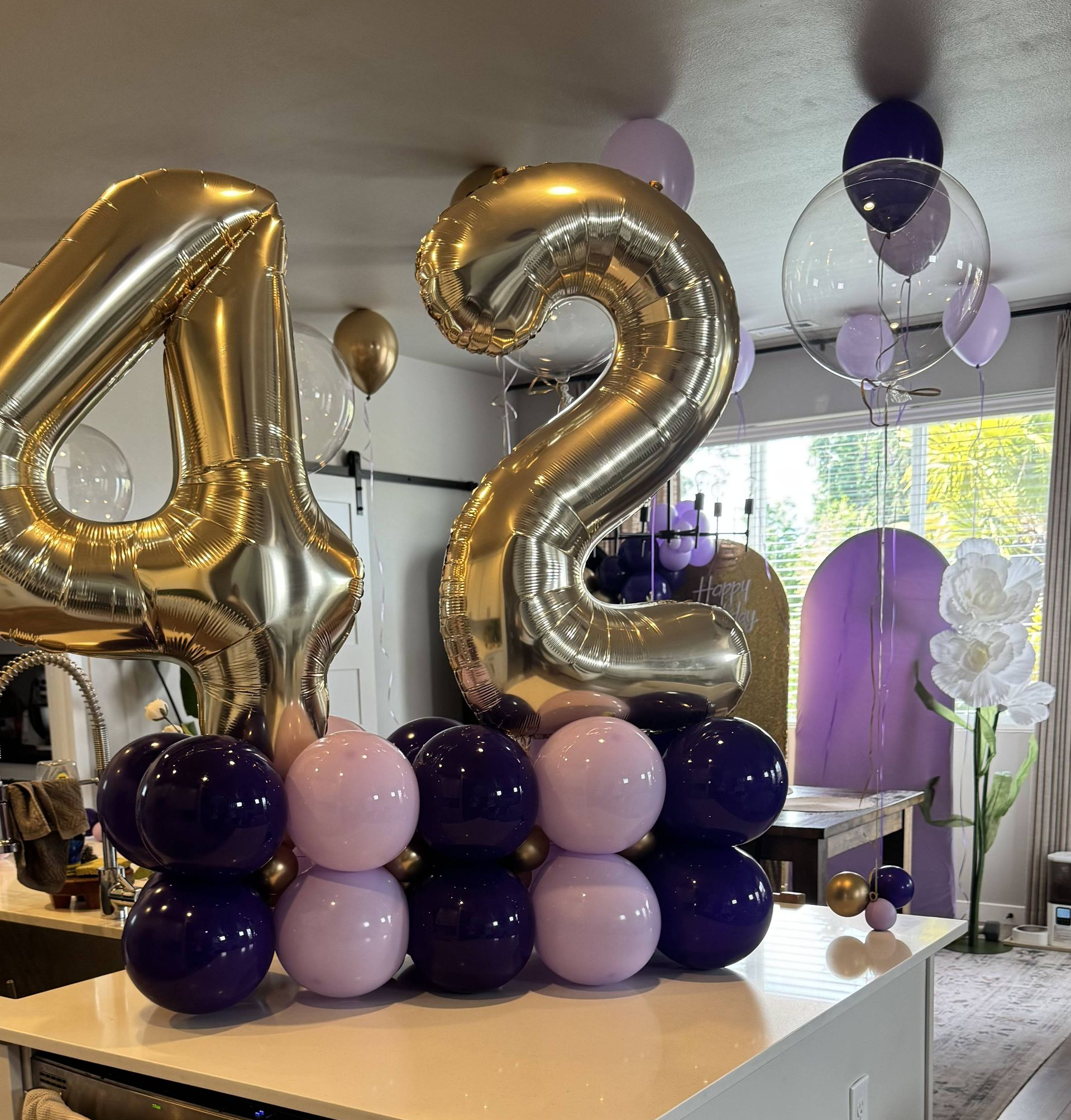 42 year old party with gold purple and clear balloons