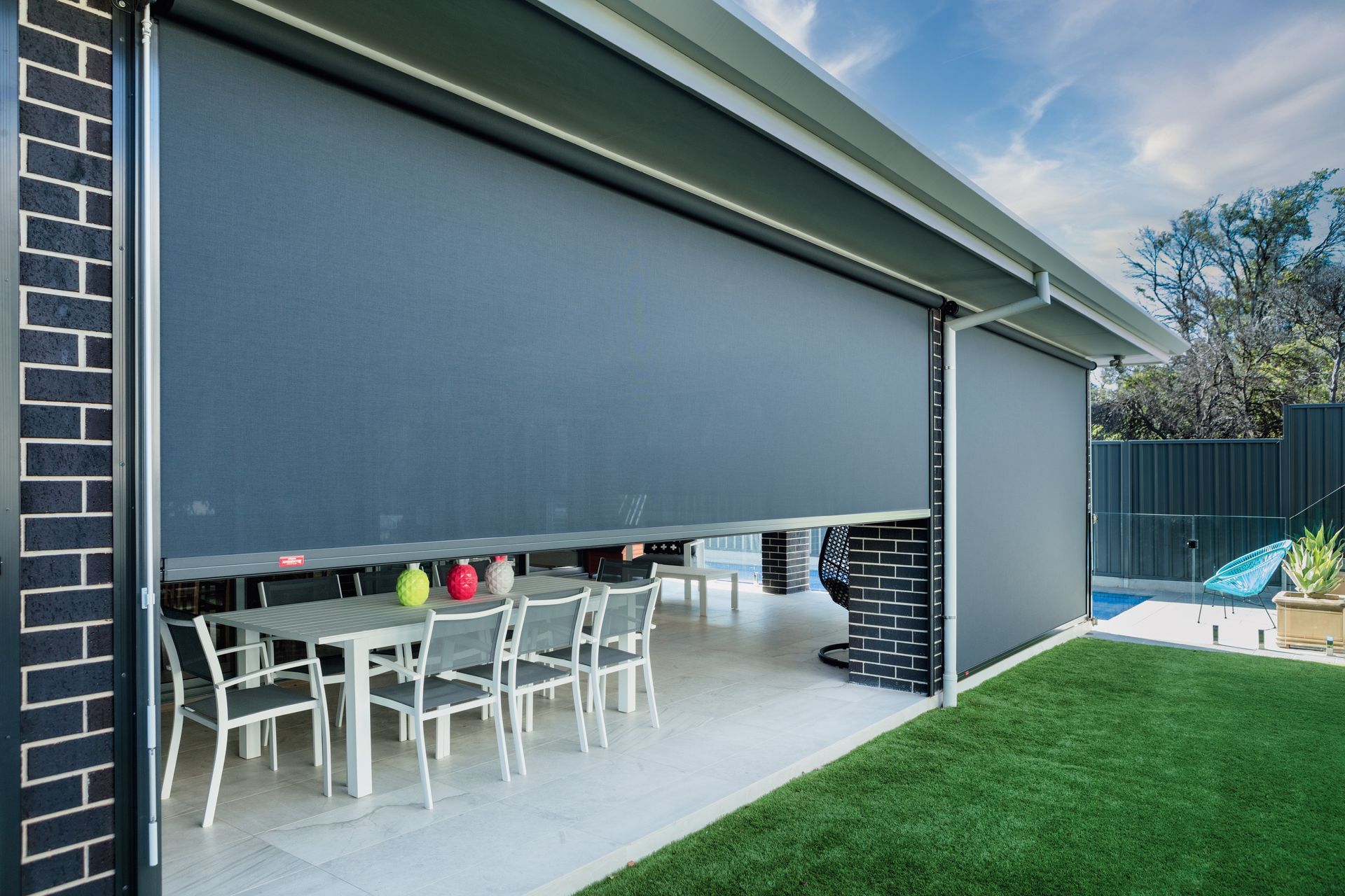 Large retractable sunshade partially open, covering an outdoor dining area. Grey fabric, brick and green lawn visible — Precision Patios Toowoomba In Toowoomba, QLD