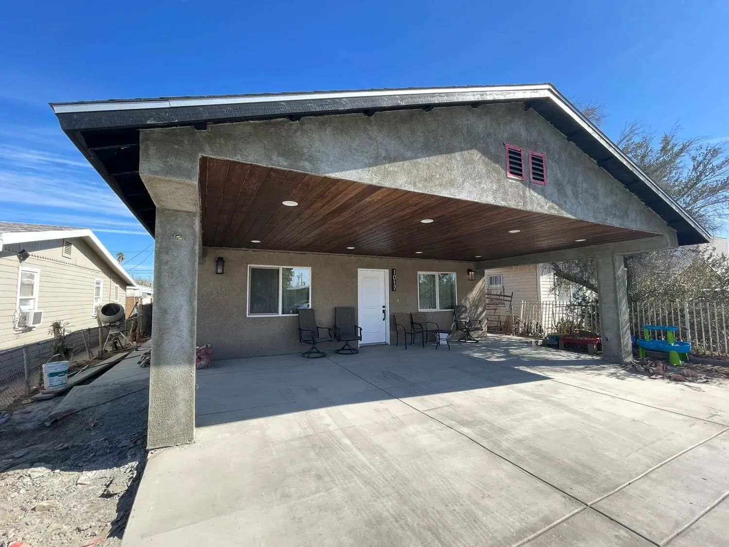 A house with a carport and a patio area in front of it.