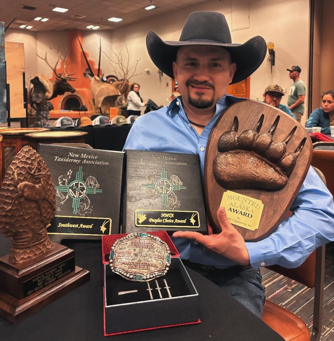 A man in a cowboy hat is holding a bear paw plaque