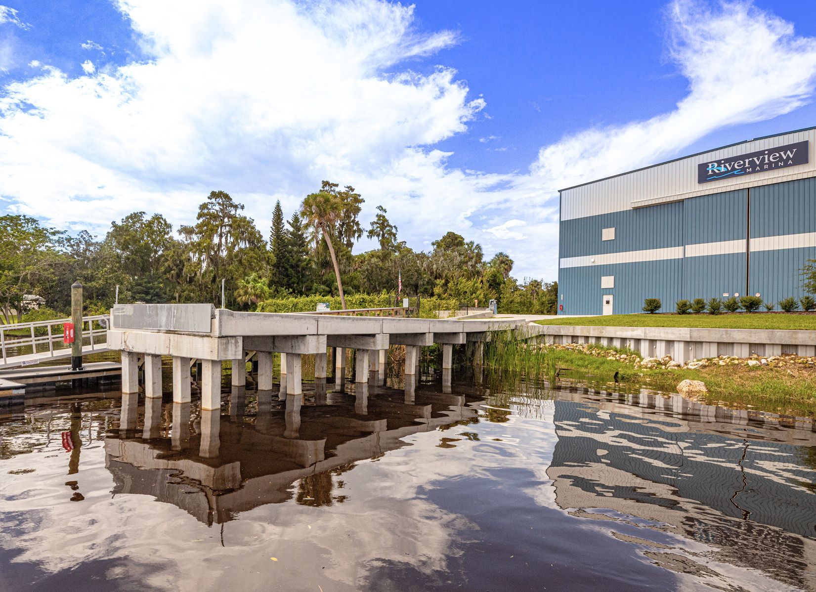 A bridge over a body of water with a Riverview Marina boat storage building in the background.