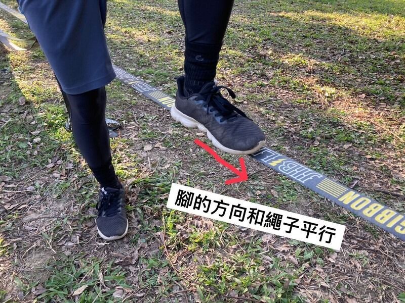 A person is walking on a tightrope in the grass.