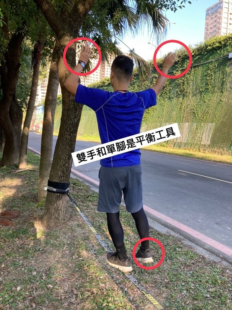 A man is standing next to a tree with his arms outstretched.