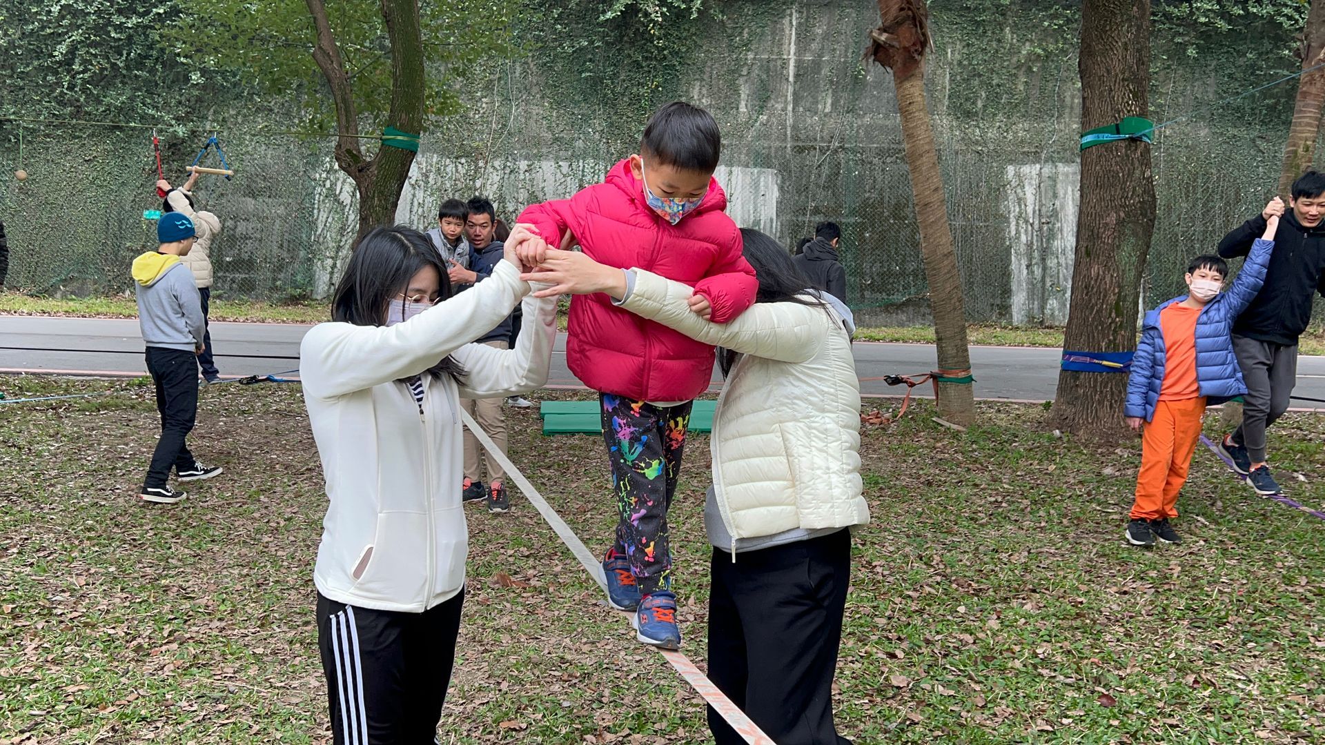 A group of children are playing with a rope in a park.