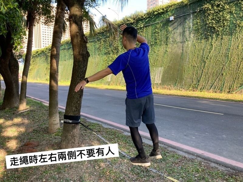 A man is standing next to a tree on the side of a road.