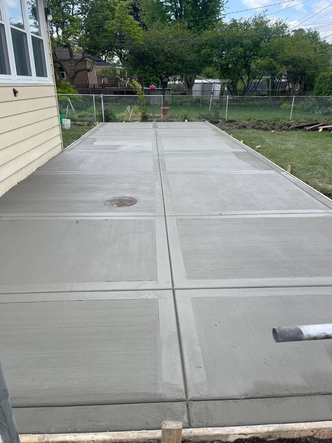 Dark gray stamped concrete patio next to a light siding building.