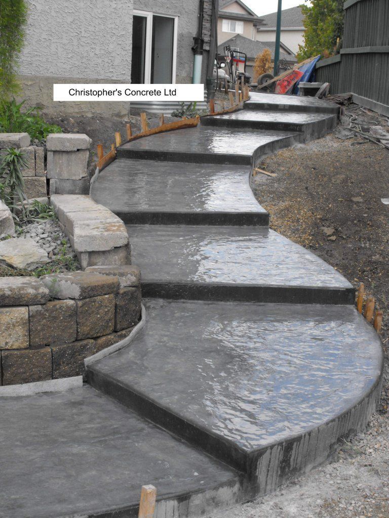 People smoothing wet concrete with a trowel, outdoors.