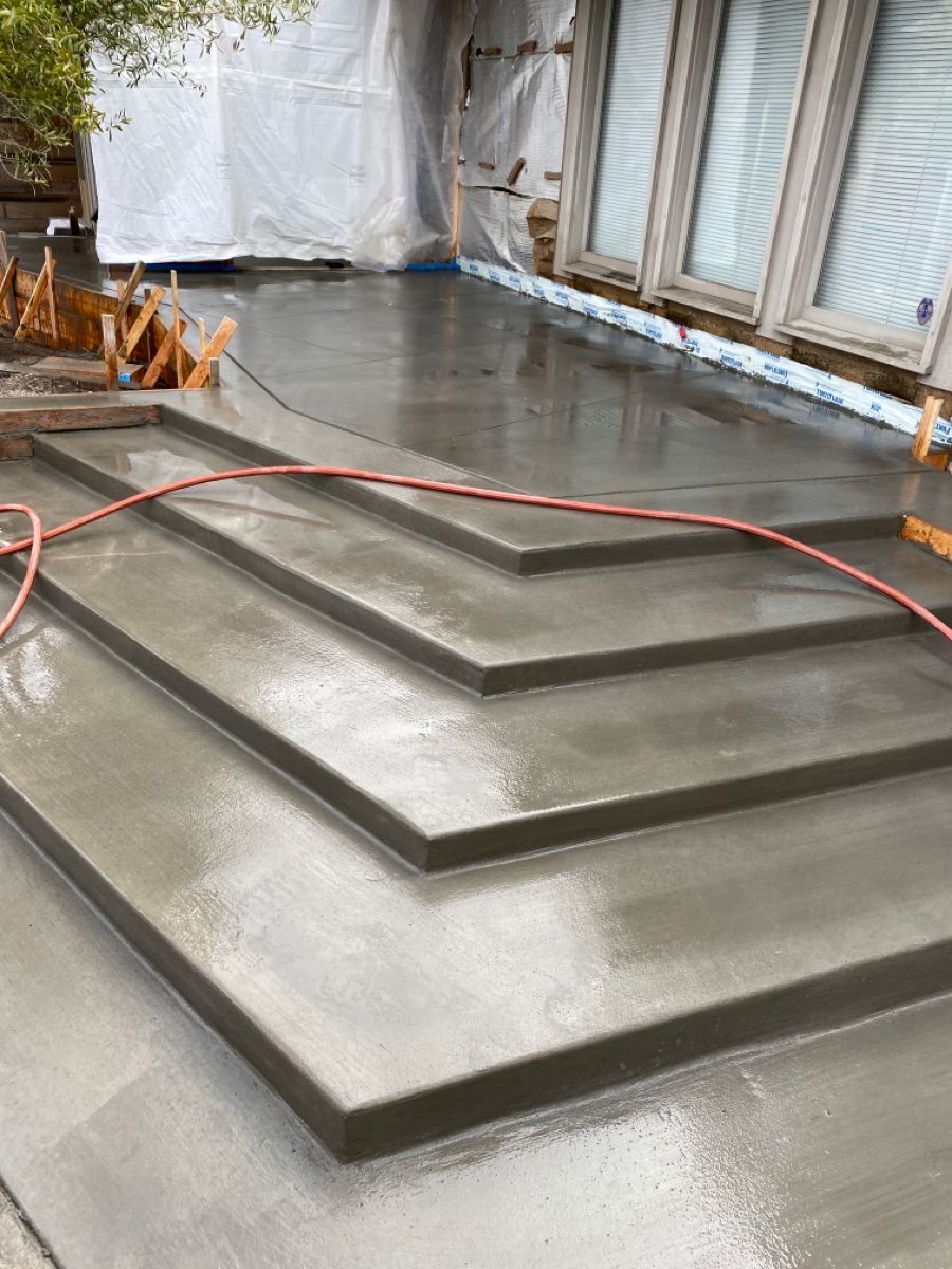 Concrete steps with metal handrails leading to a building entrance. A person is near the glass doors.
