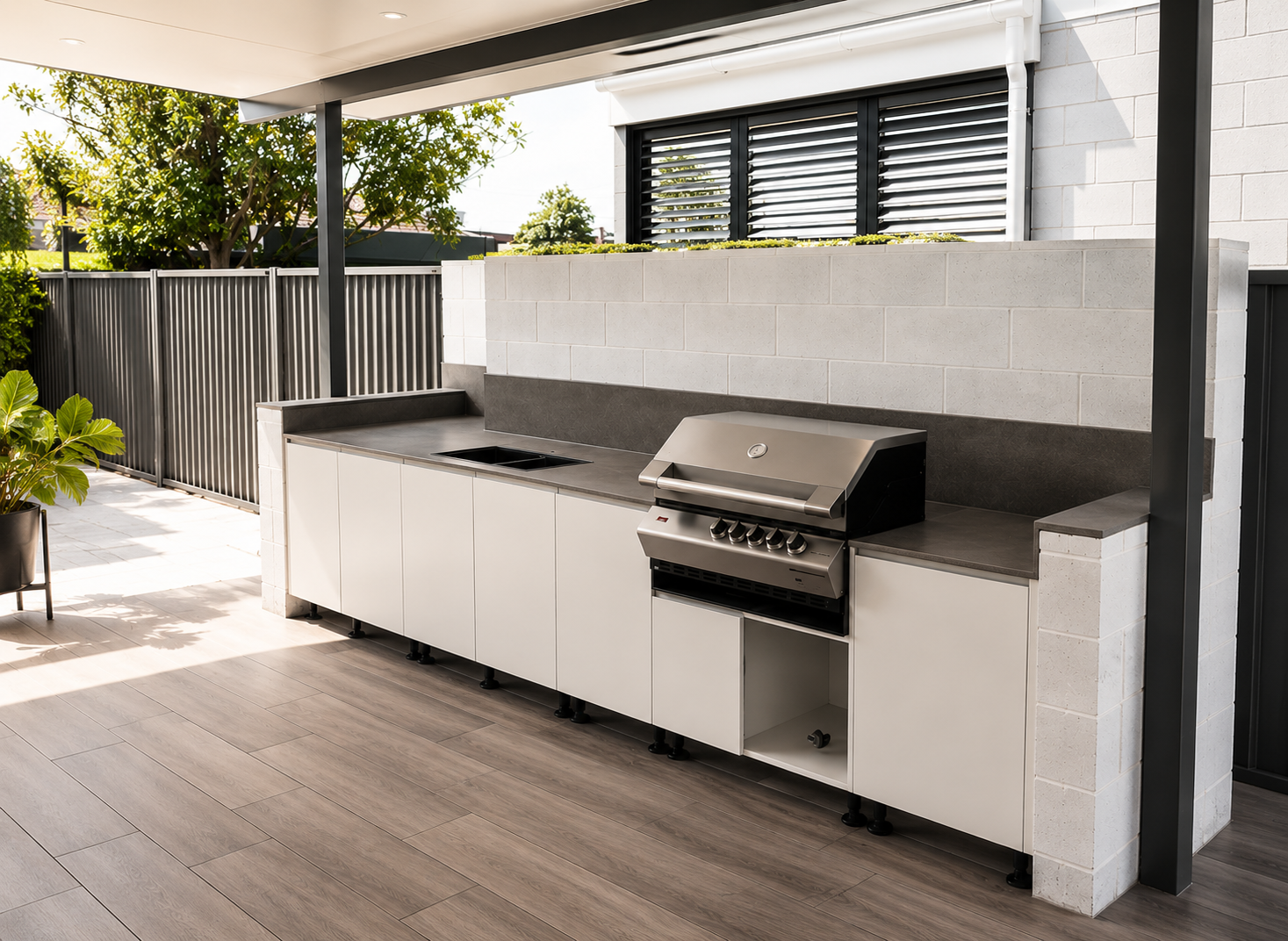 Covered outdoor patio with a built-in white grill and cabinets beside a dining area
