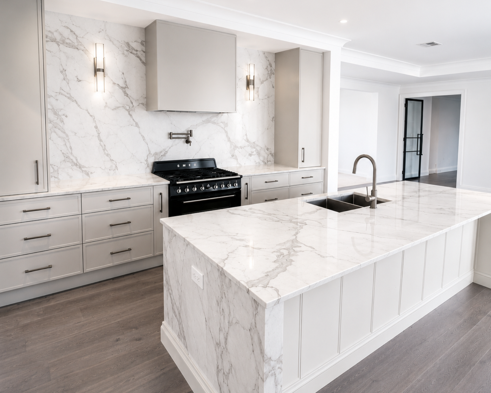 Bright modern kitchen with white marble island, black stove, and gray cabinetry