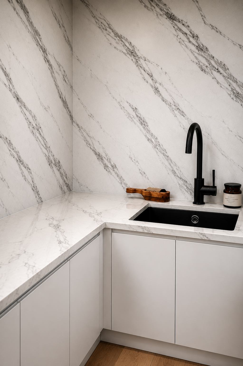 Modern white kitchen corner with marble-look walls, black sink and faucet, and light cabinets.